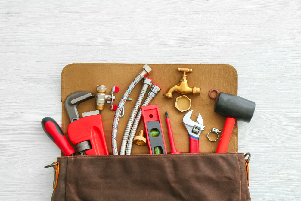 Bag with plumbing tools and items on a white table