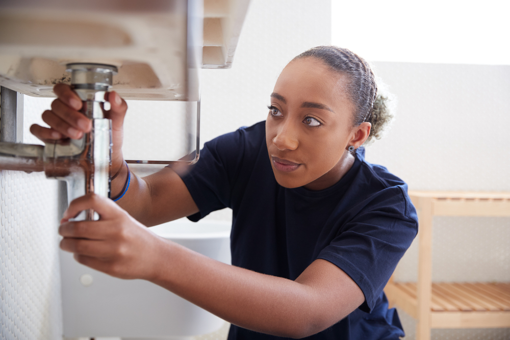 Female plumber working to fix a leaking sink in the bathroom