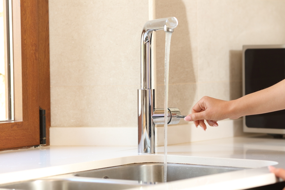 Close up of a woman's hand turning on a kitchen tap