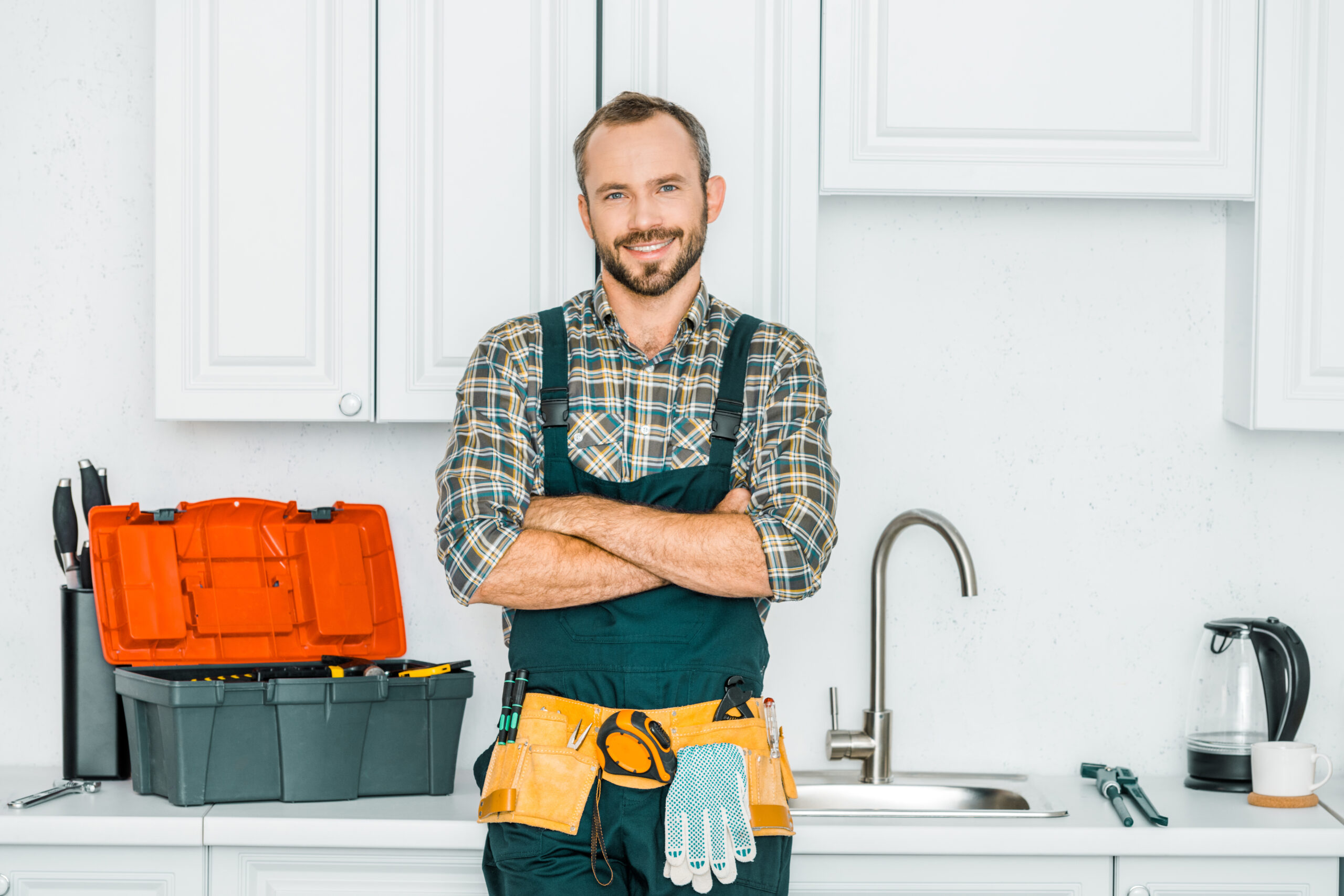 A plumber standing next to his toolbox in front of a kitchen sink