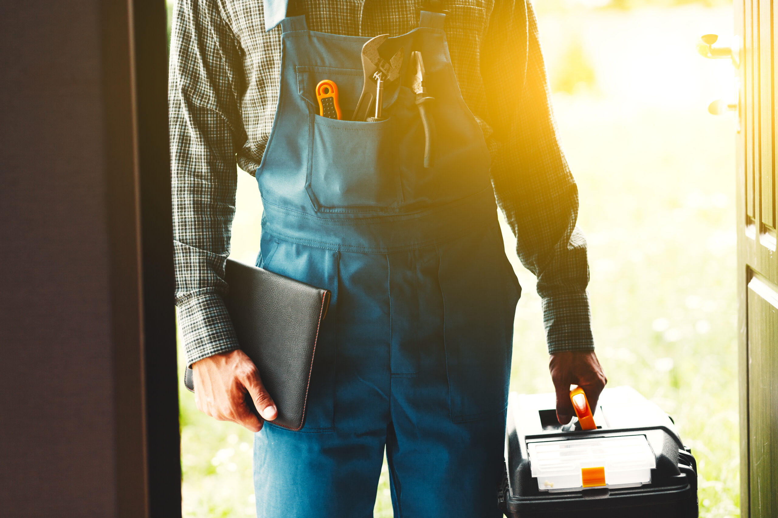 A plumber wearing overalls holding tools
