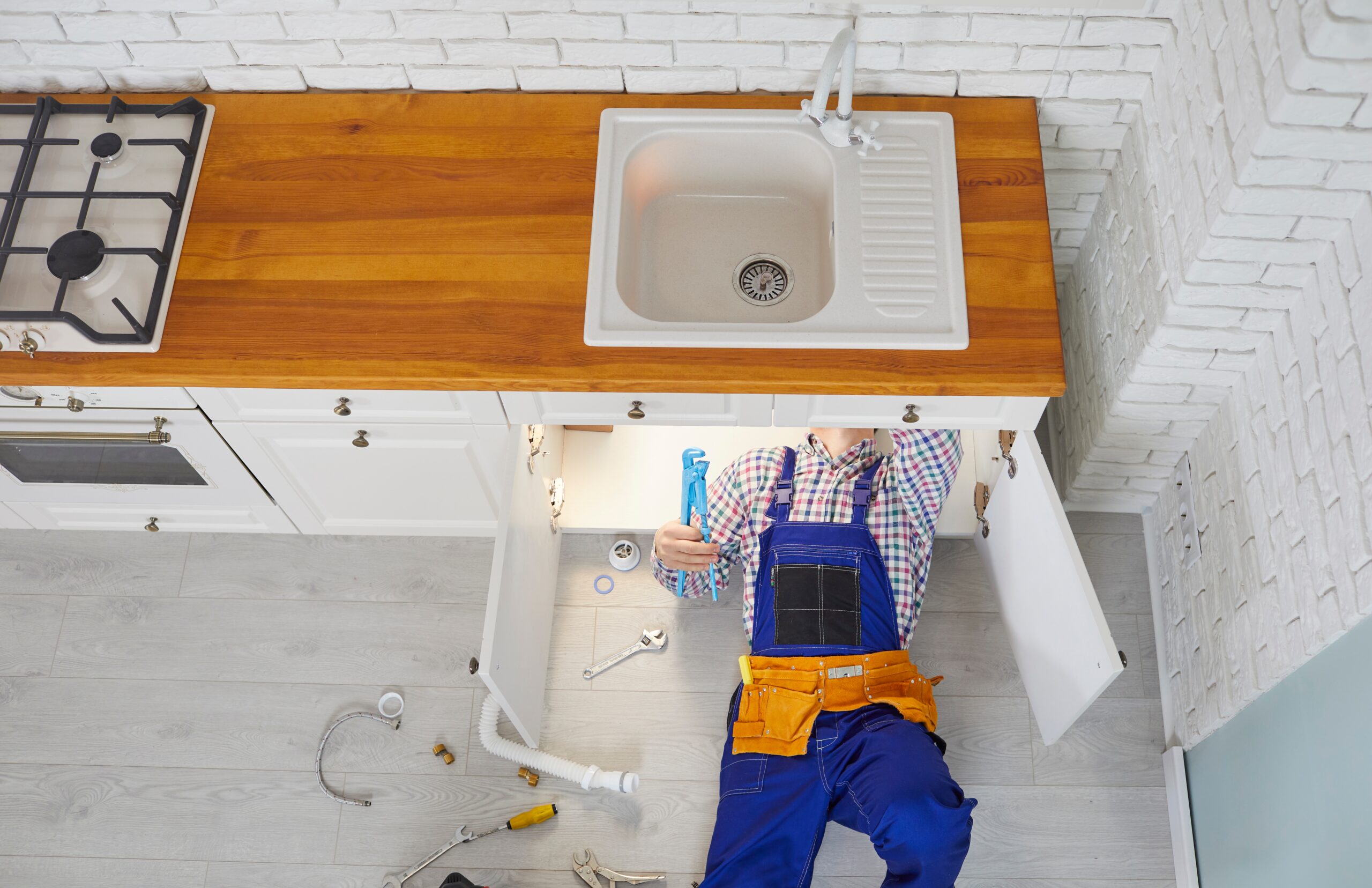 Top down view of a residential plumber working under a kitchen sink