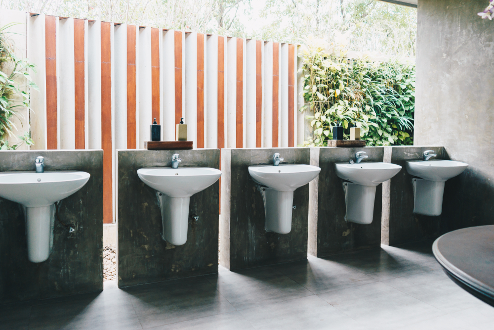 A series of five sinks in the bathroom of a commercial building