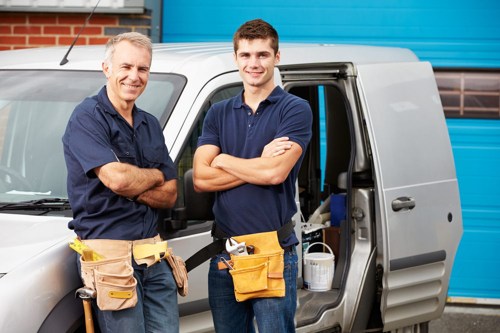 Two plumbers standing in front of a work van