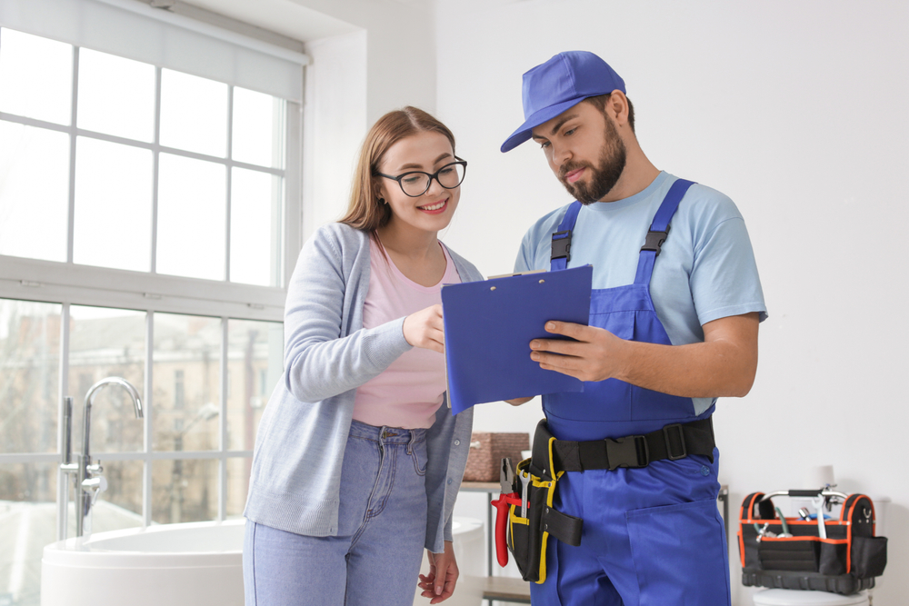 Plumber holding a clipboard showing a woman a quote